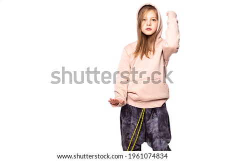 a girl of European appearance in a tracksuit raised her left hand and lowered her right hand expressing the emotions of peace of mind or showing some kind of object or inscription copy space