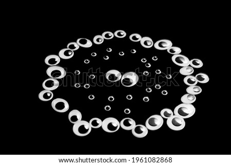 A circle of toy eyes. filled with small eyes on a black background