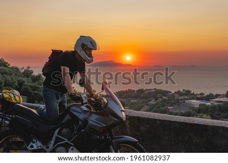 Motorcyclist man enjoy beautiful sunset, sea and mountains. Tourism and adventure. Motorcycle tour journey. copyspace for your individual text. Capri, Sorrento, Italy