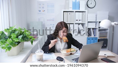 asian young woman eat her lunch and tapioca ball tea while she is working in the office