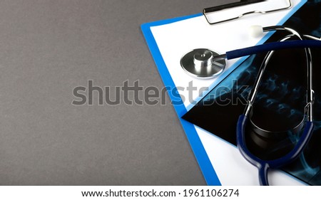medical theme - doctors desk with documents and stethoscope and mri on gray background