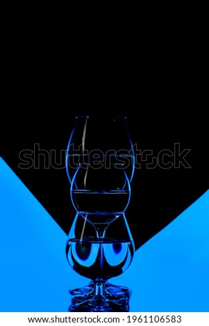 Three Different Glass Cups Placed in One Line Against Black And Blue Background. Vertical Composition