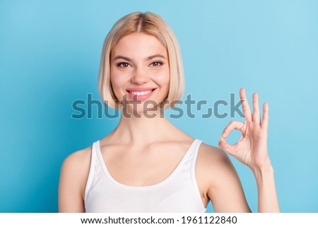 Photo of pretty positive girl toothy smile fingers show okey symbol isolated on blue color background
