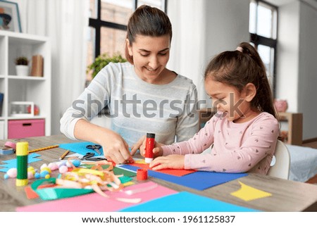 family, art and craft concept - mother spending time with her little daughter with glue making applique of color paper at home Royalty-Free Stock Photo #1961125837