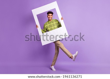 Full length body size of young man keeping photo frame cadre smiling on photo isolated on pastel violet color background