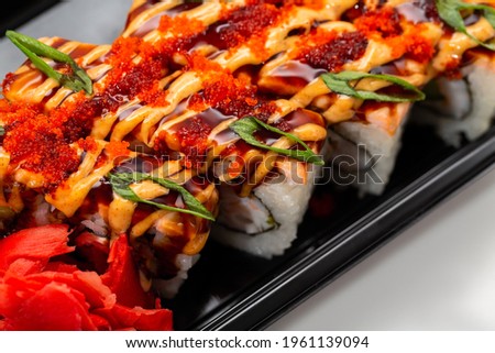 Asian rice and fresh fish rolls with hot sauce garnished with sliced onions and red fish roe. Stock image of exotic oriental food close-up