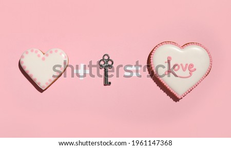 Composition with heart shaped gingerbreads and key for Valentine's day on pink background, flat lay