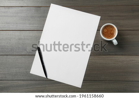 Blank paper sheet, pen and cup of coffee on wooden table, flat lay. Space for text
