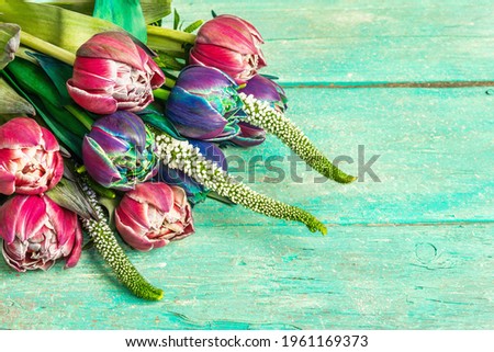 A bouquet of unusual multicolored tulips. Fresh flowers, holiday gift concept. Old wooden turquoise boards background, a place for text