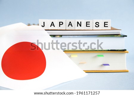 the inscription japanese on a stack of textbooks, books, exercise books and national flag of Japan, the concept of education and learning foreign languages. Royalty-Free Stock Photo #1961171257