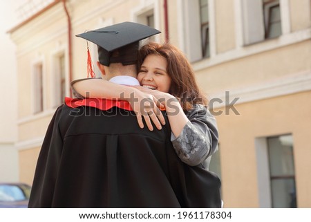 Happy Mother hugs her son student in graduation gown and a square cap after the graduation ceremony Royalty-Free Stock Photo #1961178304