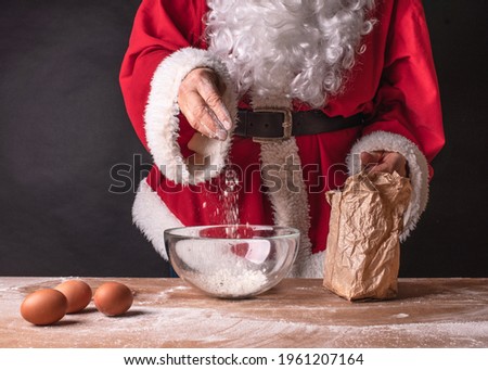 Santa preparing to bake pancakes, pastries. Red santa clothes on a black background.