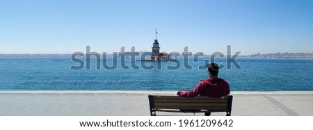 Maiden tower background, Vacation and travel to istanbul. Man relaxes on bench looking over bosphorus and enjoying Maiden Tower view. Maiden Tower is best of Popular destinations in Turkey, istanbul.  Royalty-Free Stock Photo #1961209642
