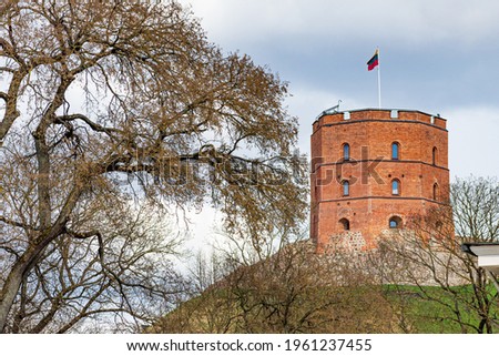 Gediminas Tower or Castle, the remaining part of the Upper Medieval Castle in Vilnius, Lithuania with Lithuanian flag on the top in a sunny day with clouds and dramatic sky on background