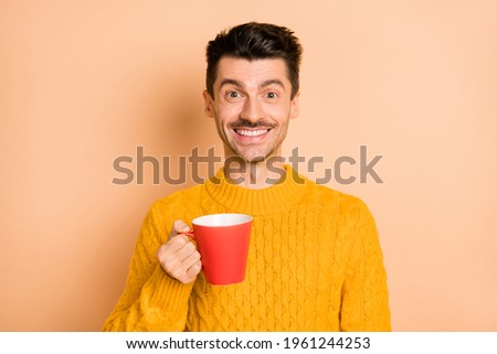 Photo portrait of cheerful smiling man drinking coffee keeping cup isolated on pastel beige color background