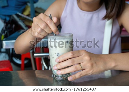 A photo of a girl enjoying a glass of traditional Vietnamese mixed sweep soup in a roadside restaurant