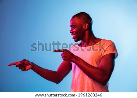 One young African man isolated on gradient background in neon light