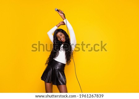 Photo portrait of funky girl holding microphone at party dancing smiling isolated bright yellow color background copyspace
