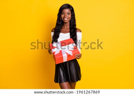 Photo of happy festive dark skin young woman hold present box holiday isolated on yellow color background