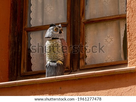 An owl-shaped scarecrow on the exterior window sill