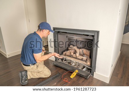 Service technician repairing a gas fireplace in a home Royalty-Free Stock Photo #1961287723