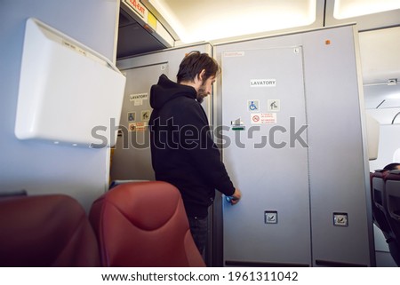 man in black clothes goes to the toilet on the plane
