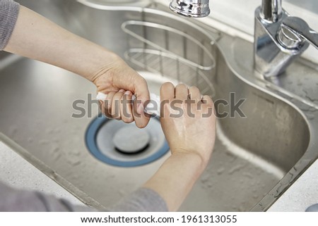 A hand washing a dishcloth on a sink Royalty-Free Stock Photo #1961313055