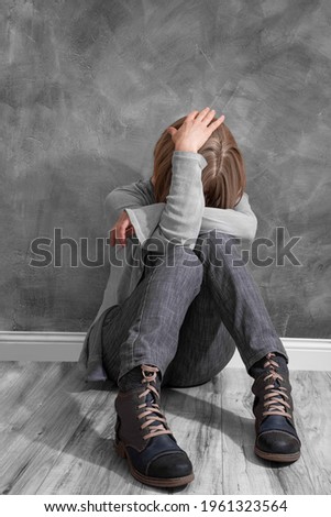 sad girl sitting against wall