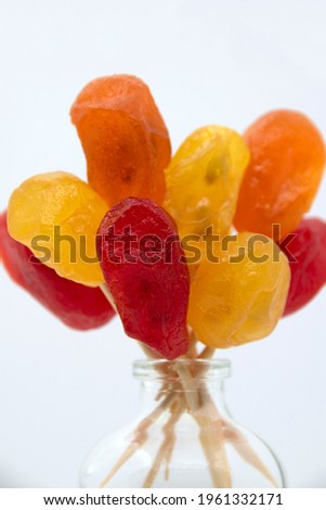 Bright yellow, orange, red candied kumquat in a transparent bottle. Dried fruits.