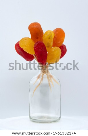Bright yellow, orange, red candied kumquat in a transparent bottle. Dried fruits.