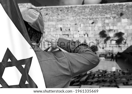 Israeli soldier with Flag of Israel salutes on the blurred background of Western Wall in the Old City of Jerusalem in Israel Royalty-Free Stock Photo #1961335669