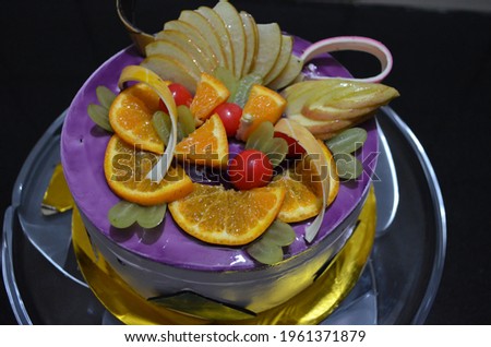 Fruit cake with fresh fruits decoration. Apple, cherry, orange and grapes decoration. Blue berry cake with icing. Glazed.
