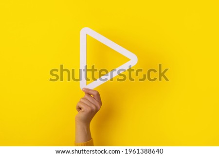 hand holding 3d media play button over yellow background