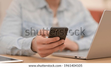 Male Hands Using Smartphone next to Laptop, Close up