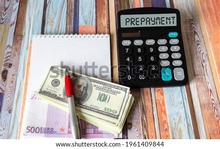 The word PREPAYMENT on a calculator, next to euros and dollars. Business and taxes concept.