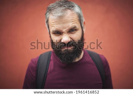 Portrait of funny man looking at camera. angry expression. Young and brutal. Male barber care. Mature hipster with beard. brutal caucasian hipster with moustache. Hair and beard care. Serious face.