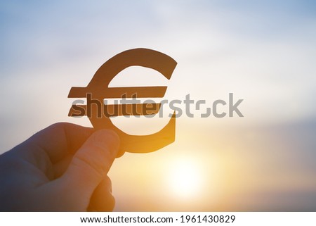 EURO currency symbol in the hand of a businessman against the backdrop of the sunset. Banking, business finance, course