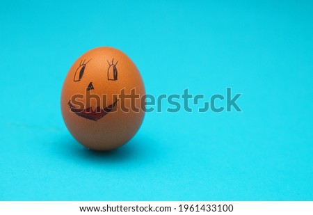 Chicken eggs with painted faces on a blue background. The concept of the Easter holiday. Egg decoration.Empty space for the text.