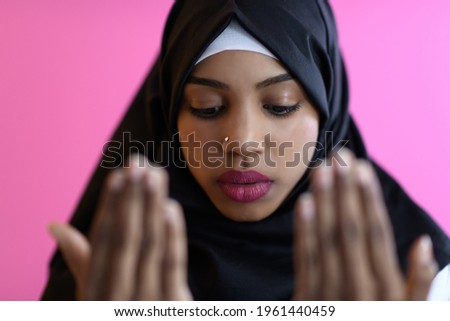 Modern African Muslim woman makes traditional prayer to God, keeps hands in praying gesture, wears traditional white clothes