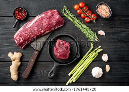 Raw beef meat steak Tenderloin fillet mignon set, in cast iron frying pan, on black wooden table background, top view flat lay