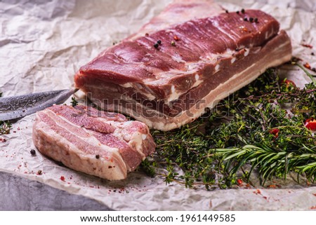 Raw fresh beef ribs steak with seasoning on a light surface, parchment, before cooking. Seasoning for meat steak with ribs for eyes rosemary, coriander, pepper. Top view, lying flat