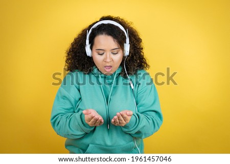 Young african american girl wearing gym clothes and using headphones Smiling with hands palms together receiving or giving gesture. Hold and protection