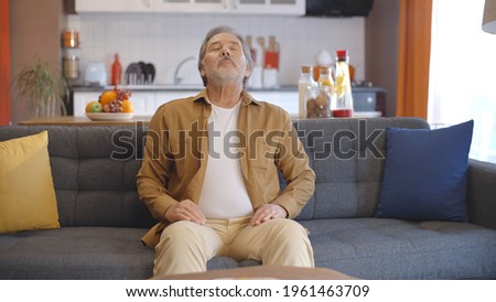 Breathing deeply at home, the old man breathes peacefully and yawns. Breath at home concept. Breath and peace concept.Peaceful home concept.  Royalty-Free Stock Photo #1961463709