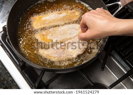 Pan-frying or home cooking fish fillet on a stove top. Royalty-Free Stock Photo #1961524279