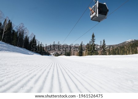 Gondola lift in the ski resort on steep slope groomed and prepared for skiing