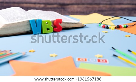 Church background with Abbreviation "VBS" (Vacation Bible School) next to black bible . Copy space text. Selective focus.