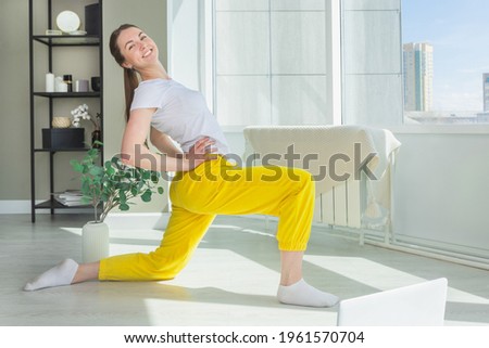 Young woman doing pilates online. The girl does morning exercises. Online fitness workshop concept.