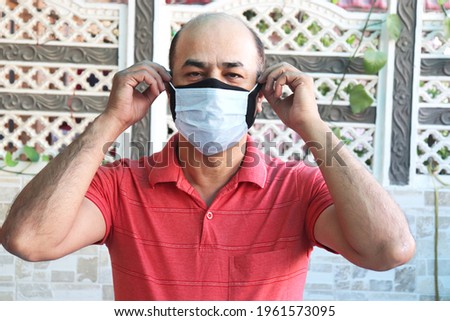 double mask prevent infection, mature indian man wearing two face mask to protect from new strain of coronavirus or new wave of omicron virus outbreak in india.