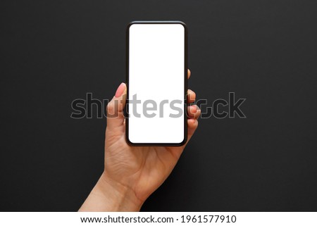 Person holding phone in one hand on dark background