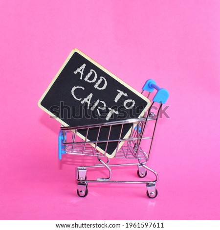 Close up image of shopping trolley with text ADD TO CART isolated on pink background